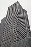 Ground-level view of a modern skyscraper with a gray-tinted, all-glass facade