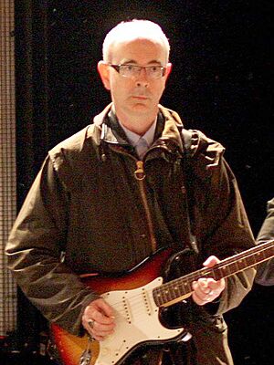 Dik Evans holding a guitar in front of a microphone stand