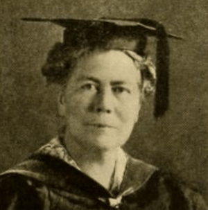 An older white woman in academic robes and a mortarboard cap, from 1920 yearbook