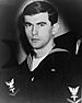 Head and shoulders of a young white man wearing a dark sailor suit with an eagle patch on the upper sleeve.