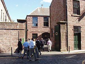 A crowd of visitors enter the former jute factory's courtyard, surrounded by sandstone-built, Georgian-style industrial buildings.