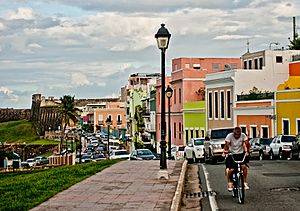 Cars, houses, street light, man on bicycle and El Morro in Old San Juan