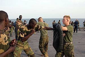US Navy 051103-M-2175L-200 U.S. Marine Corps Lance Cpl. Ryan Papa, right, assigned to 2nd Platoon, Company C, 1st Battalion, 8th Marine Regiment, holds a striking pad for a member of the Senegalese 90th Naval Infantry