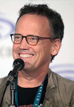 smiling dark-haired man with glasses at microphone