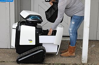 Woman Takes Groceries from Dax Delivery Robot