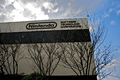 A gray, nondescript building with "Nintendo" written on the top floor, and with trees in the foreground.