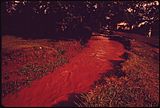 A reddish brown stream cuts through a residential area