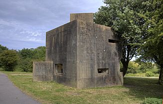 View of an irregularly shaped concrete building with gun slits built into the walls at different levels