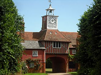 Brick and timber gatehouse topped by a small clock tower
