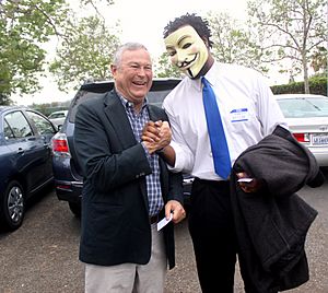 U.S. Congressman Dana Rohrabacher shakes hands with a supporter wearing Guy Fawkes mask