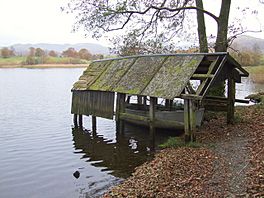 A derelict boathouse extending out onto a lake