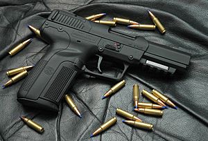 Photo of an all-black Five-seven USG pistol surrounded by 5.7×28mm SS197SR cartridges