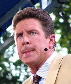 Color head-and-shoulders shot of Marino, in jacket and tie, wearing broadcaster's headset.