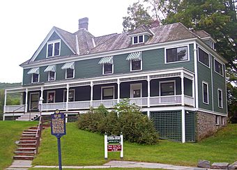 A green and white house with peaked roofs and awnings