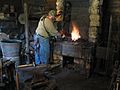 A modern-day blacksmith forging at John Deere House and Shop