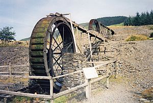 Photograph of two water wheels, one in the foreground and one in the background, each fed water by a wooden launder