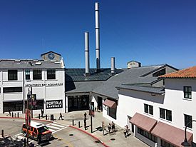 Three smokestacks come out of a glass ceiling above the aquarium's main entrance with white, windowed façades on either side