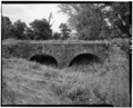 VIEW, SOUTH ELEVATION, LOOKING NORTH (SCALE ROD IS MEASURED IN FEET) - Milltown Bridge, Spanning Vache Grasse Creek tributary at County Road No.77, Milltown, Sebastian County, AR HAER ARK,66-MILTO,1-1