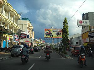 City street with cars, motorbikes and a billboard