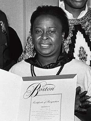 Black and white photograph of Watson, holding a certificate of recognition