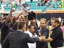 Coach Teddy Keaton holds up Championship Trophy