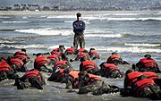 US Navy 030415-N-3953L-039 During a Hell Week surf drill evolution, a Navy SEAL instructor assists students from Basic Underwater Demolition-SEAL (BUD-S) class 245 with learning the importance of listening