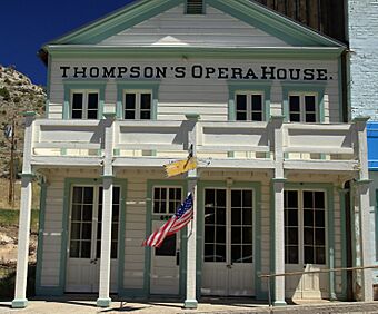 Two-story wooden, white building with blue trim and a large porch