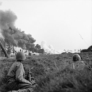 A convoy of Allied lorries under enemy artillery and mortar fire on the road between Son and Eindhoven, Holland, 20 September 1944. In the foreground American paratroopers shelter in a ditch. BU1062