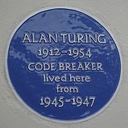 A Blue plaque on a white wall with the words "Alan Turing 1912–1954 CODE BREAKER lived here from 1945 – 1947