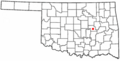 A white map of Oklahoma with a red dot in the center