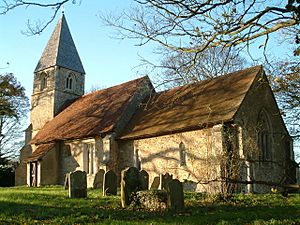 A stone church with red tiled roofs seen from the southeast, showing the chancel, the nave at a higher level, and at the far end the tower with a pyramidal roof