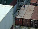 Hafenarbeiter bei ihrer gefährlichen Arbeit auf den Containern in der Luke