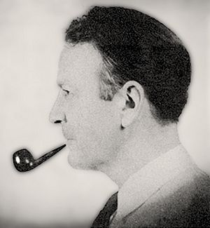 Man with slicked-back black hair facing left, smoking a pipe