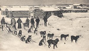 Early 20th century view of Circle City, as a sled dog team prepares to leave for Fort Gibbon with the mail.