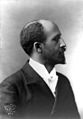 A formally dressed African American man, sitting for a posed portrait