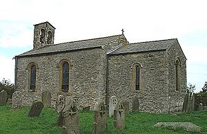 A small, simple stone church.  On the left is the nave with a bellcote at the far end, and on the right a smaller chancel