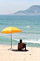 Man sitting under beach umbrella