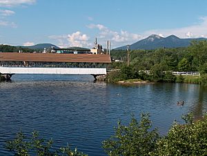 Covered bridge over the Upper Ammonoosuc River in front of former paper mill in Groveton.  The Percy Peaks are in the distance.