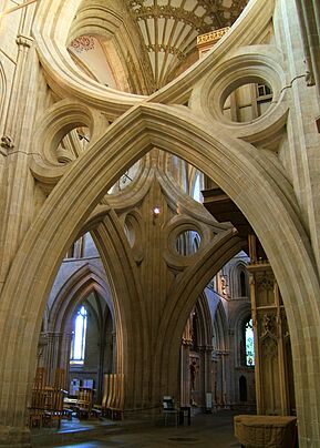 A huge undecorated Gothic arch spans the width of the cathedral nave, with an inverted arch above it, giving  scissors-like appearance  