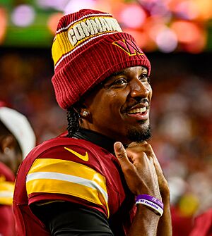 A photo of Jayden Daniels smiling and wearing a Washington Commanders uniform during an NFL game
