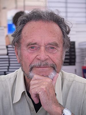 View from the collar up of a smiling man in his 80s with receding headline and a gray beard.