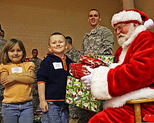 Pvt. Evan Allen Dancer, center, smiles as Santa Claus, right, hands gifts to Destiny Hawley and her brother Justin Hawley of Scipio, Ind., during the 3rd Annual Operation Christmas Blessing event at Muscatatuck 111212-A-QU728-005