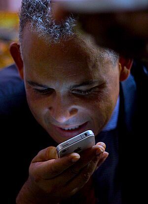 Headshot of Fils-Aimé looking down and speaking into an iPhone