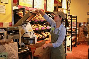 An employee places a bagel in a slicer machine at a Panera Bread restaurant