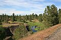 A rail trail overlooking a stream in a shallow valley