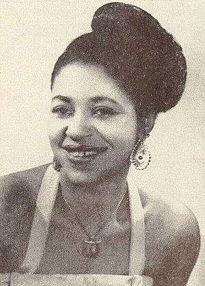 Portrait of a young black woman in a sundress with her hair in a bun wearing a large pendant necklace and large teardrop earrings