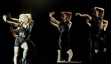 Madonna dancing with a group of dancers wearing black outfits