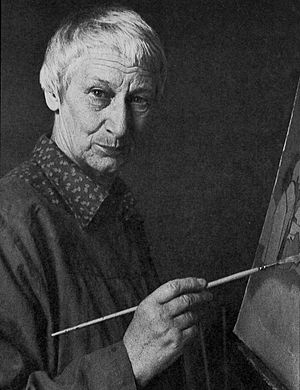The artist Rita Angus posed holding a paintbrush. A canvas is visible in the right part of the image.