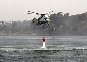 US Navy 031029-N-8590B-016 Two UH-3H Sea King helicopters assigned to the Golden Gaters of Helicopter Combat Support Squadron Eighty Five (HC-85) dip their Bambi bucket into a lake to aid in the firefighting effort