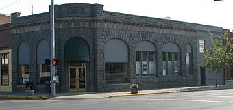 Photograph of a one-story, stone commercial building on a city street corner